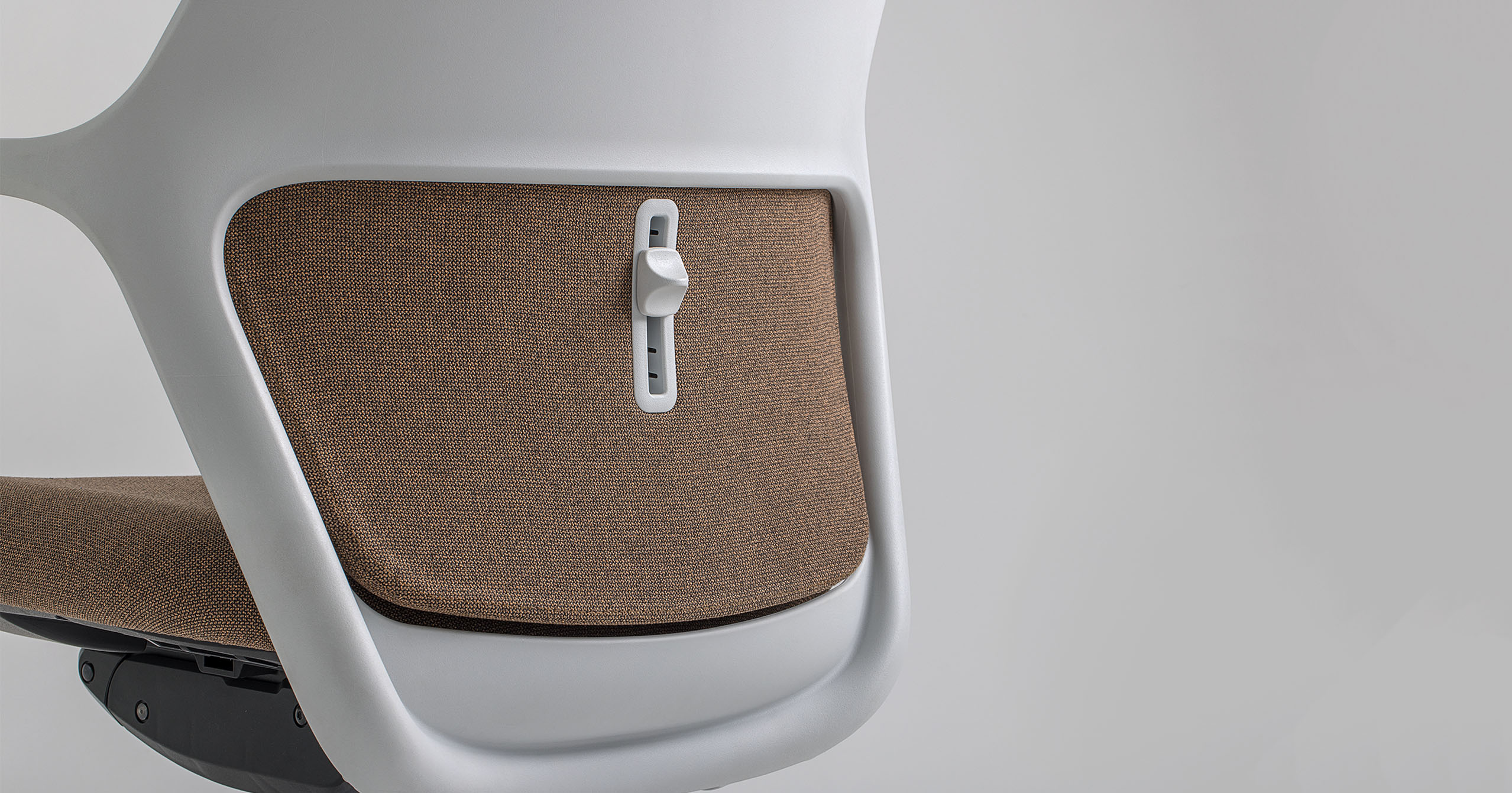 Close-up of the backrest adjustment knob on the OFY chair designed by Alegre Design for Narbutas. The chair features a brown fabric finish and ergonomic design, including adjustable lumbar support for enhanced comfort in modern office environments.