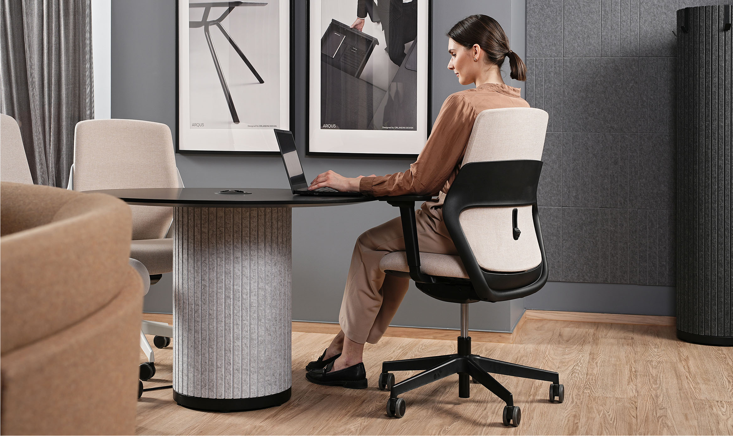 A woman working at a desk seated in an OFY chair designed by Alegre Design for Narbutas. The image highlights the chair's ergonomic design, adjustable lumbar support, and suitability for modern office environments.